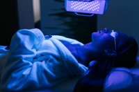 Woman lying down with eyes covered receiving blue LED light therapy on face