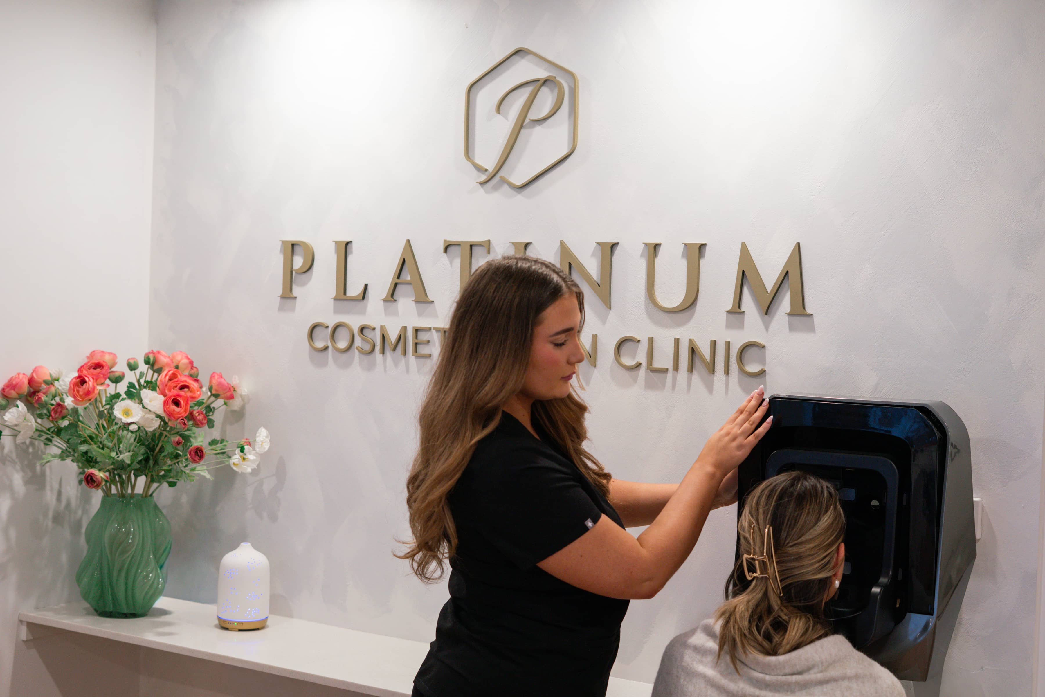 Clinician assisting client with facial skin analysis device at Platinum Cosmetic Skin Clinic reception